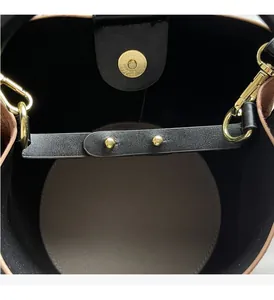 Detail of golden magnetic clasp and hardware on a textured bucket bag interior