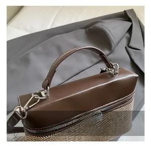 Close-up of contrast stitching handle and silver zipper on herringbone pattern handbag