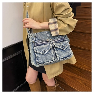 Détail d'un sac cabas en jean bleu vintage avec plusieurs poches à boucle et zips métalliques