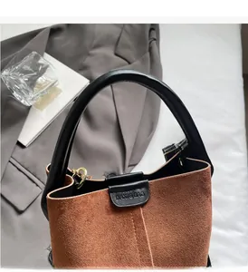 Detailed top view of a brown suede bucket bag with black leather handle and gold hardware