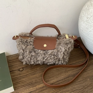 Close-up of grey plush fleece crossbody bag with brown leather flap and golden button