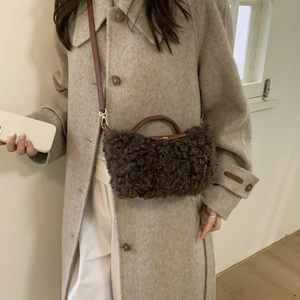 Detail of dark brown plush crossbody bag with faux fur texture and leather strap