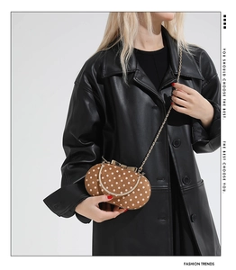 Close-up of vintage polka dot suede handbag with gold bow clasp and metal chain strap