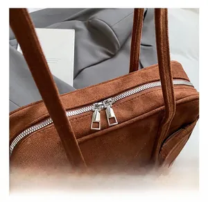 Gros plan sur les fermetures éclair argentées d'un sac cabas vintage en daim marron