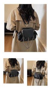 Detailed view of black quilted leather backpack with gold chain straps on a khaki trench coat