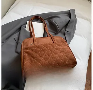Détail du fourre-tout en daim marron avec poche matelassée et texture rétro élégante
