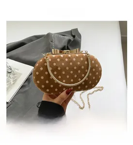 Close-up of brown polka dot bag featuring a golden bow metal clasp and chain strap