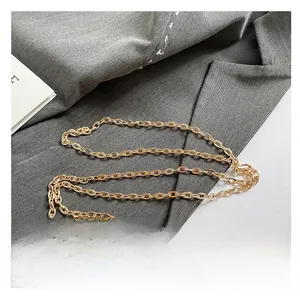 Detailed close-up of golden metal chain strap on brown polka dot shoulder handbag