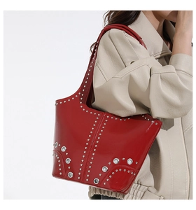 Detailed close-up of glossy red leather shoulder bag with silver studs and eyelets