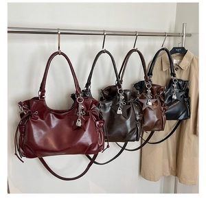 Détail des sacs cabas en similicuir en bordeaux, café, marron et noir avec pendentifs