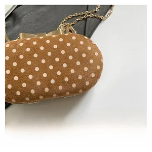 Detail of brown suede polka dot handbag with gold bow clasp and metallic chain strap