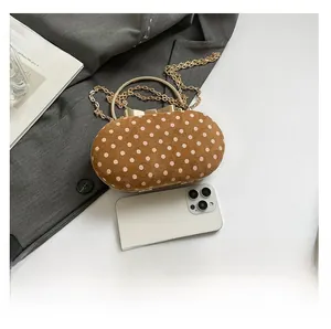 Polka dot handbag size comparison with a smartphone and elegant gold chain strap