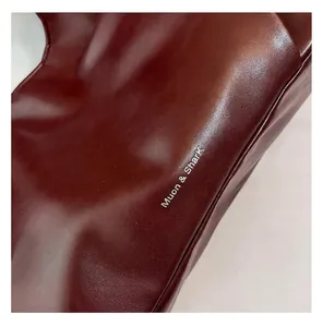 Gros plan d'un sac cabas en cuir ciré bordeaux avec un logo argenté élégant