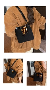 Detail view of black suede bucket bag with gold clasp and decorative vintage beads