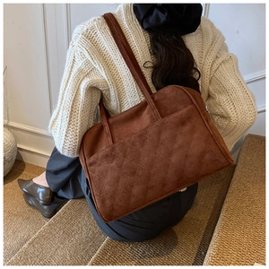 Détail du sac cabas en daim marron avec surpiqûres élégantes et texture mate raffinée