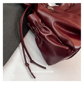 Détail macro du sac en cuir bordeaux avec cordon de serrage et coutures précises
