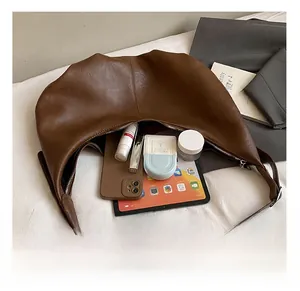 Spacious interior of brown pebbled leather crescent bag holding a tablet and cosmetics
