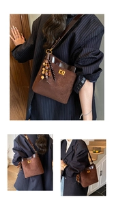 Close-up of brown suede bucket bag featuring polished dark leather trim and golden lock