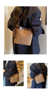 Detail of vintage suede bucket bag featuring contrast leather trim and golden twist lock