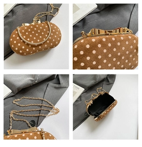 Detail view of brown polka dot suede bag with golden bow clasp and metal chain strap
