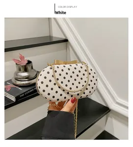 Chic white polka dot handbag with golden bow clasp and metallic chain strap detail