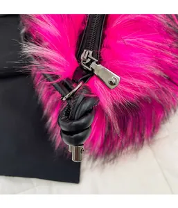 Detail of a bright pink faux fur bag with a black zipper and knotted leather handle