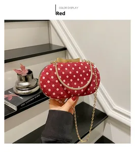 Detail of red polka dot velvet handbag with golden bow clasp and chain strap
