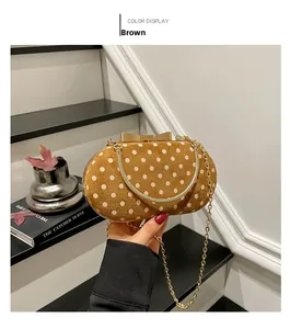 Close-up of brown suede polka dot handbag with gold bow clasp and metal chain strap