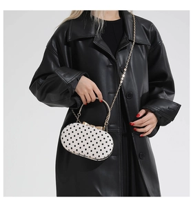 Polka dot handbag detail showing golden curved handle and metallic bow closure clasp