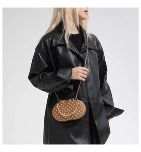 Close-up of brown polka dot chain bag with gold bow clasp on black leather coat