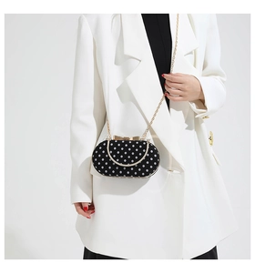 Polka dot evening clutch with golden chain strap and bow clasp on a white suit