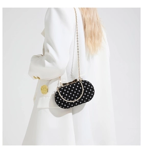 Close-up of black velvet polka dot evening bag with gold bow clasp and metal chain