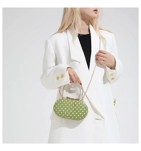 Macro shot of green polka dot handbag featuring gold metal handle and bow clasp detail