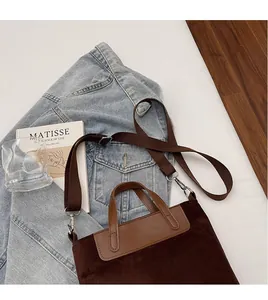 Detail of brown suede tote bag with wide adjustable shoulder strap and leather handles