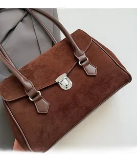Close-up of brown suede shoulder bag showing silver metal lock and refined texture