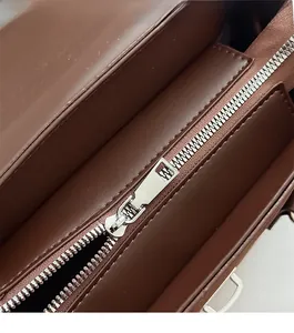 Close-up of smooth silver metal zipper and fine stitching on brown suede leather bag