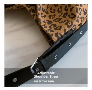 Detail of adjustable black leather strap with silver eyelets on a leopard print bag