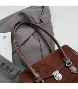 Detail of dark brown faux suede shoulder bag with silver twist lock and smooth leather strap