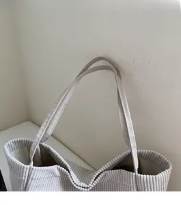 Gros plan sur les bandoulières en velours côtelé beige d'un grand sac cabas