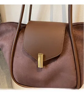 Close-up of vintage dark brown suede tote with luxury gold hardware and leather flap