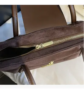 Detail view of smooth golden zipper closure on premium dark brown suede bucket bag