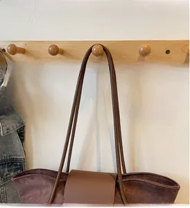 Detail view of large brown vintage frosted tote bag hanging on a wooden hook