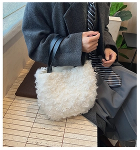 Detail of white plush bucket bag featuring soft faux fur texture and black leather handles