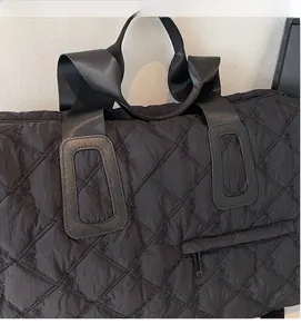 Detail of black quilted travel bag featuring floral embroidery and soft nylon texture