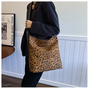 Detailed view of large leopard print tote bag with a black wide shoulder strap on a model