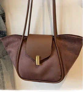 Macro view of vintage matte suede tote bag featuring brown leather trim and gold metal clasp