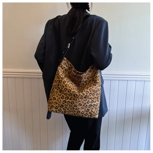 Detail view of large leopard print tote bag with adjustable black shoulder strap on model