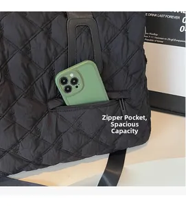 Detailed view of black quilted tote bag featuring floral embroidery and a zipper phone pocket