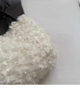 Close-up of white curly faux fur fabric texture with soft plush feel on a shoulder bag