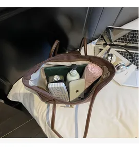 Spacious interior of dark brown leather tote bag holding a phone, umbrella, and cosmetics